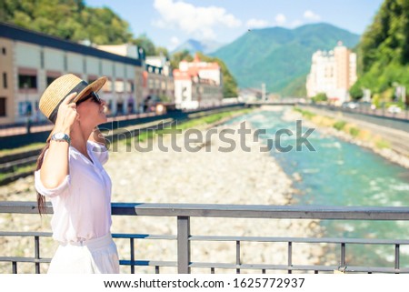 Beautiful woman in hat on the embankment of a mountain river in the city.