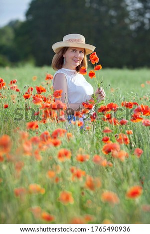 beautiful woman in a hat in a poppy field in summer