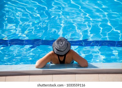 Mujer hermosa con sombrero relajante al borde de la piscina