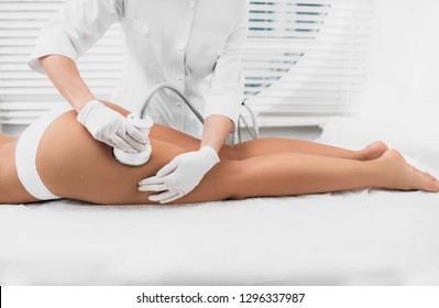 Beautiful woman having cavitation, procedure removing cellulite on legs and buttocks at beauty clinic