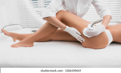 Beautiful woman having cavitation, procedure removing cellulite on legs and buttocks at beauty clinic