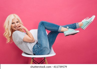 Beautiful Woman Having Fun On The Chair Over Pink Background