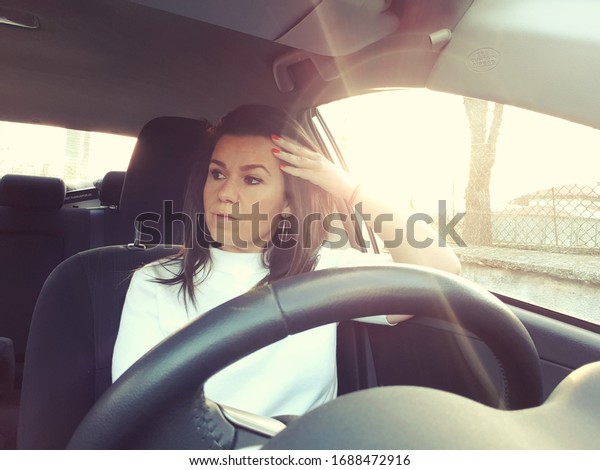 Beautiful woman  having\
a problem   with a car sitting inside holding her head with hands\
waiting for help