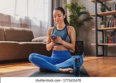 Beautiful woman in headphones looking at smartphone, listening music and relaxing after training - Powered by Shutterstock