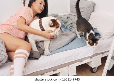 Beautiful Woman With Her Cat And Dog On  Bed. Shedding And Pet Dander Allergy Concept