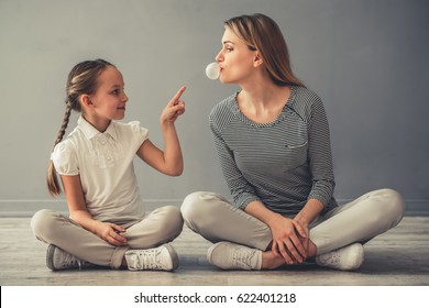 Beautiful Woman And Her Cute Little Daughter Are Playing With Chewing Gum While Sitting On The Floor