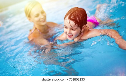 Beautiful woman with her daughter in swimming pool - Powered by Shutterstock