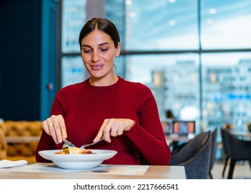 Beautiful Woman With Her Hair Pulled Back Eating In A Restaurant. Happy Woman Eating Lunch By Herself At A Restaurant