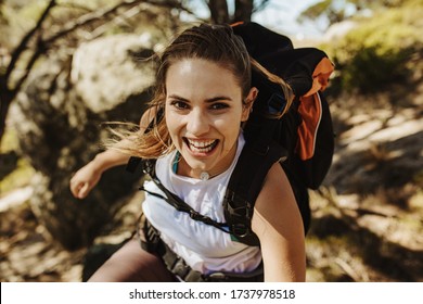 Beautiful woman hiking mountain. Female mountaineer having fun while climbing a mountain with a backpack.