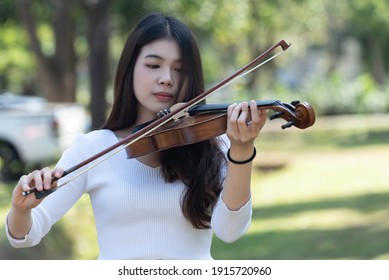Beautiful woman hold violin on nature view background, in emotion feeling happy.
