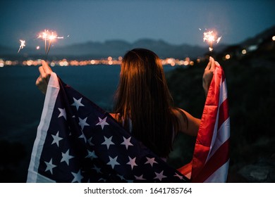 Beautiful woman holding American flag celebrating holding sparkles - Powered by Shutterstock