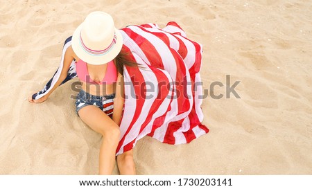 Beautiful woman holding an American flag on the beach. Travel. USA flag