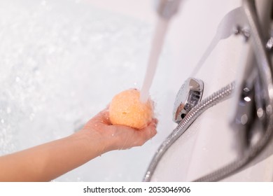 Beautiful Woman Holding An Aromatic Orange Bath Bomb On Her Hands Before Put It Into The Bathtub. Wellness And Hydro Therapy Relaxation Concept.