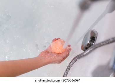 Beautiful Woman Holding An Aromatic Orange Bath Bomb On Her Hands Before Put It Into The Bathtub. Wellness And Hydro Therapy Relaxation Concept.