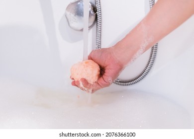 Beautiful Woman Holding An Aromatic Orange Bath Bomb On Her Hands Before Put It Into The Bathtub. Wellness And Hydro Therapy Relaxation Concept.