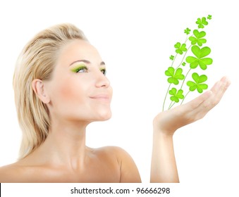 Beautiful woman holding fresh clover plant  in hand, sensual female portrait isolated on white background, cute girl with bright green makeup, st.Patrick's day holiday