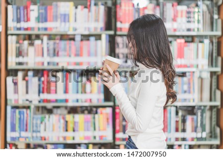 Beautiful woman holding a glass of coffee While relaxing in the library