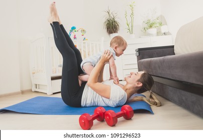 Beautiful woman holding her baby boy and exercising on floor at home