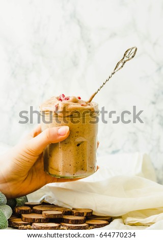 Beautiful woman holding in her hand glass jar of chocolate icecream. Melts raw vegan banana nicecream