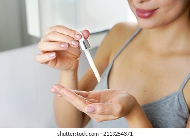 Beautiful woman holding a pipette in her hand with serum moisturizing anti aging antioxidant. Focus on hand.
