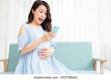 Beautiful woman holding pregnant belly and using phone - Powered by Shutterstock