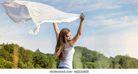 Beautiful woman holding a white scarf that flies in the wind
