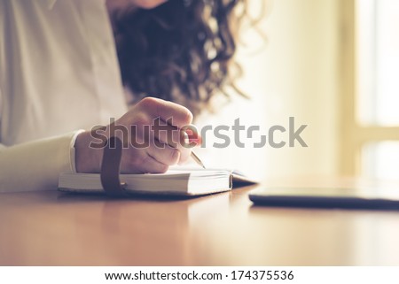 beautiful woman at home writing and working with diary and smart phone