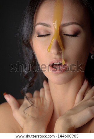 Beautiful woman with honey mask over darkgray