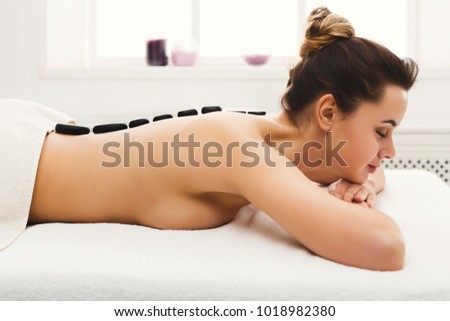 Beautiful woman at hot stones massage in spa salon. Beauty treatment therapy, wellness and relaxation concept