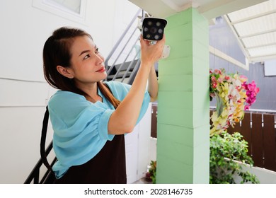 Beautiful Woman House Adjusts Direction Angle View Of CCTV Home Security Camera And Fine-tune Internet Cam For Perfect Scene Of Watching. Conept For Self-reliant And DIY Job Of Modern Housewife.