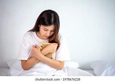 A beautiful woman hugged a photo with a sad feeling and crying in the bedroom in a sad mood.