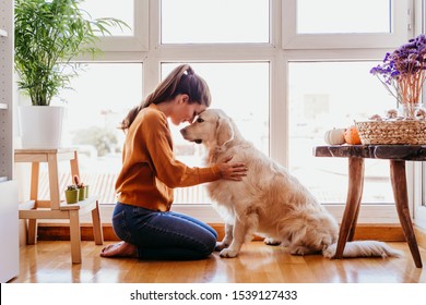 Beautiful Woman Hugging Her Adorable Golden Retriever Dog At Home. Love For Animals Concept. Lifestyle Indoors
