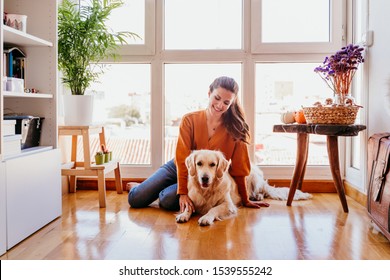 Beautiful Woman Hugging Her Adorable Golden Retriever Dog At Home. Love For Animals Concept. Lifestyle Indoors