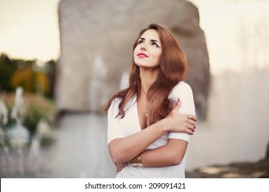 beautiful woman hugging herself near the fountain