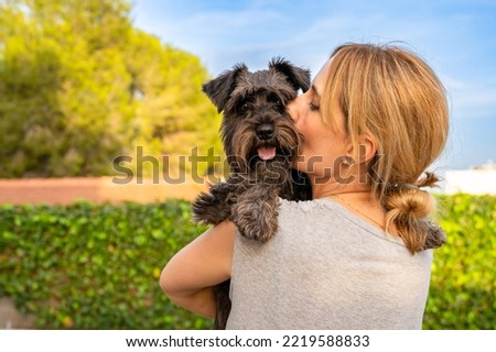 Beautiful woman hugging and kissing dog. Dog and owner together outdoors. Love and friendship between dog and owner