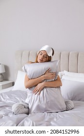 Beautiful Woman Hugging Pillow On Comfortable Bed With Silky Linens