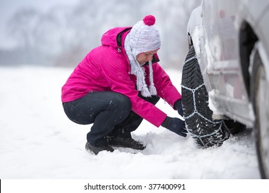 Beautiful woman  installing snow chain on her car