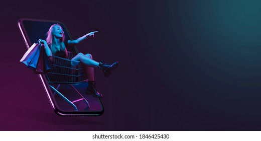 Beautiful woman inviting for shopping right from device screen, black friday, sales concept. Flyer. Cyber monday and online purchases, negative space for ad. Finance and money. Dark neon background. - Shutterstock ID 1846425430