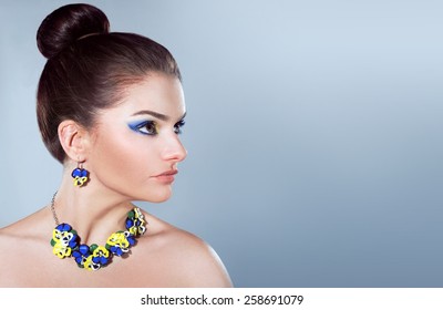 Beautiful Woman In Jewelry Of Pansies On A Gray Background