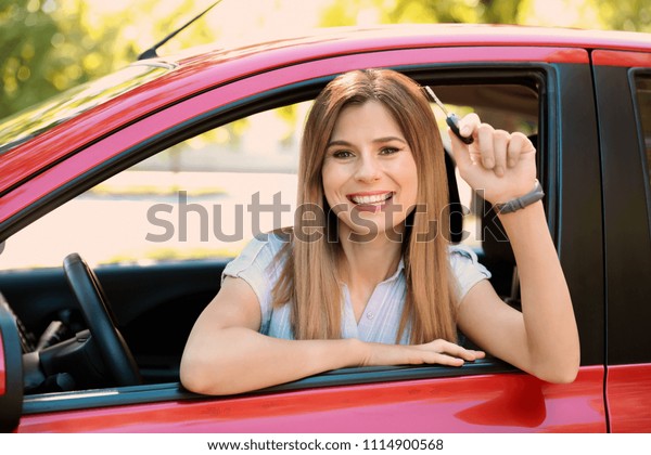 Beautiful woman with key\
sitting in car