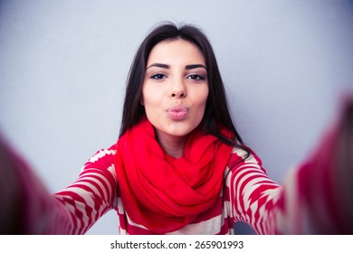 Beautiful Woman Kissing At Camera Over Gray Background. Wearing In Pink Scarf And Sweater. Looking At Camera 