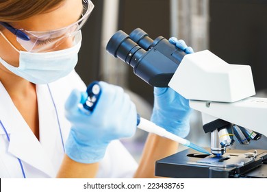 Beautiful woman in a laboratory working with a microscope.