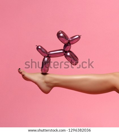Beautiful woman leg and metallic dog balloon composition on pink background