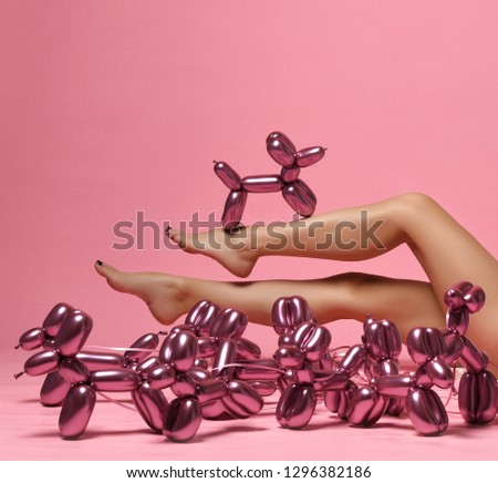 Beautiful woman legs and metallic dog balloon composition on pink background