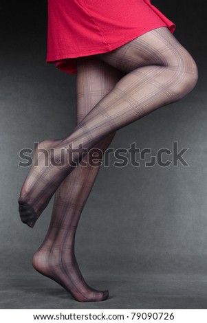 Beautiful woman legs wearing tights & red dress over grey