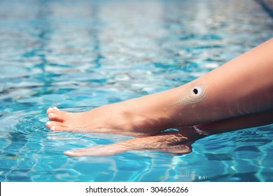 Beautiful Woman Lgs In Swimming Pool. Tanned Feet With Pedicure And Gold Tattoo In The Pool Water.