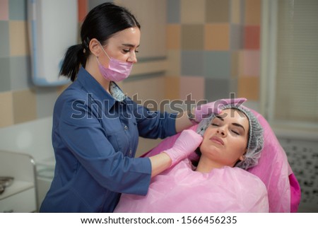 A beautiful woman lies on the procedure in a cosmetic clinic where she is injected with hyaluronic acid