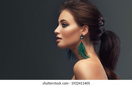 Beautiful woman with  long big earrings. Beauty girl with elegant hairstyle and evening make-up. Makeup, cosmetics and jewelry