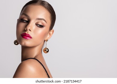 Beautiful woman with long big earrings. Beauty girl with elegant hairstyle and evening make-up. Makeup, cosmetics and jewelry