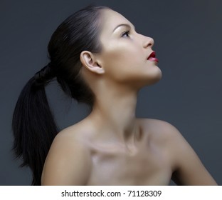 beautiful woman with long black hair in ponytail and shiny skin looking up in profile, natural make-up and beautiful skin texture